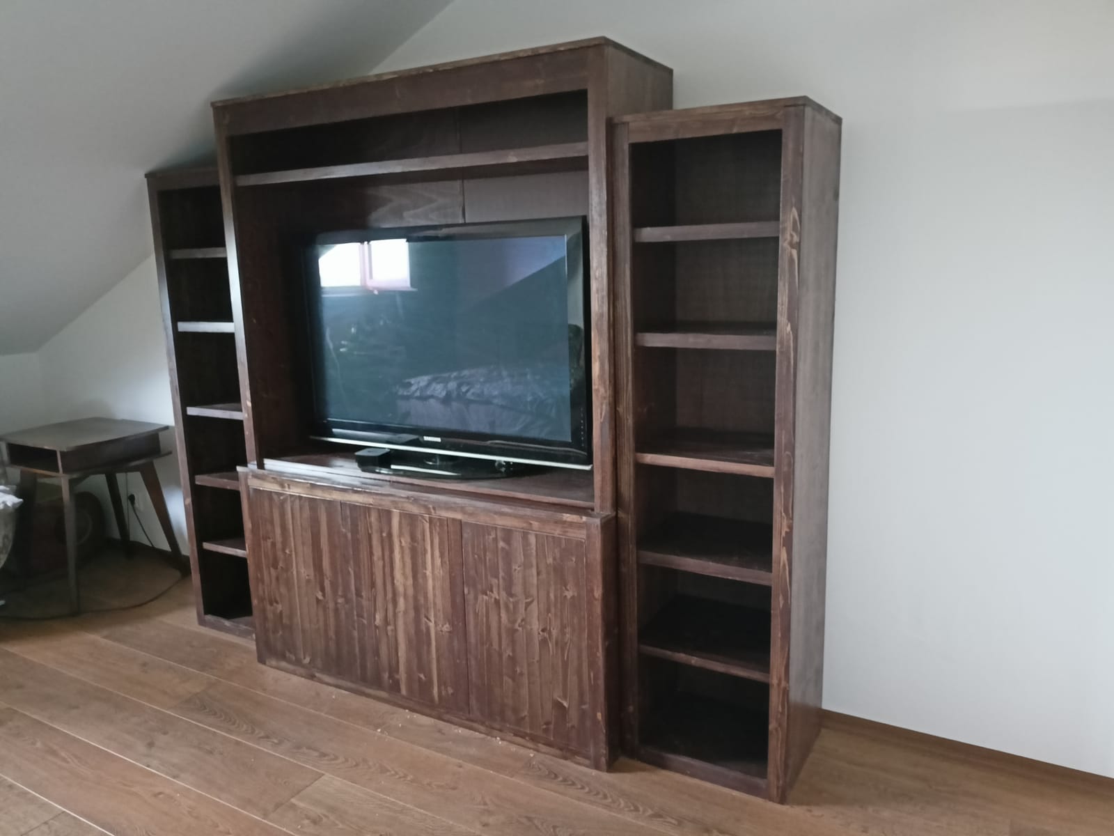 Tmavě mořená obývací stěna ze smrku s místem na televizi a bočními knihovnami